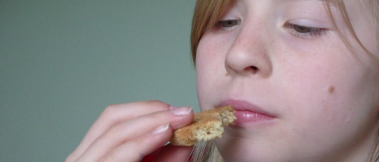 Niña oliendo comida.