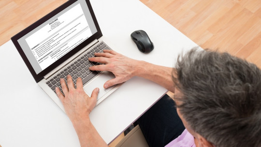 Hombre redactando un documento en un laptop.