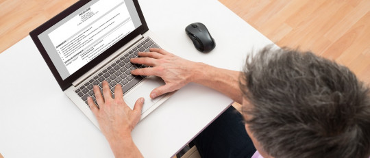 Hombre redactando un documento en un laptop.