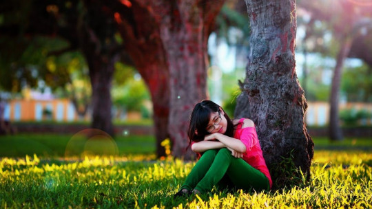 Mujer sentada bajo un árbol.