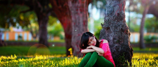 Mujer sentada bajo un árbol.