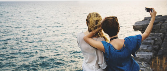Mujeres tomándose una selfie en la costa.