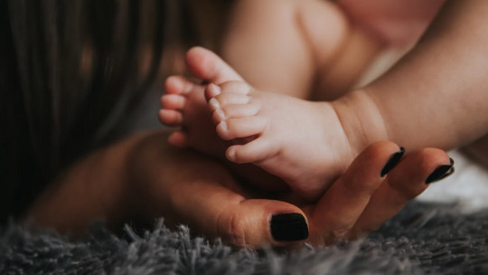 Los pies de un bebé y las manos de una madre.