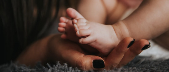 Los pies de un bebé y las manos de una madre.