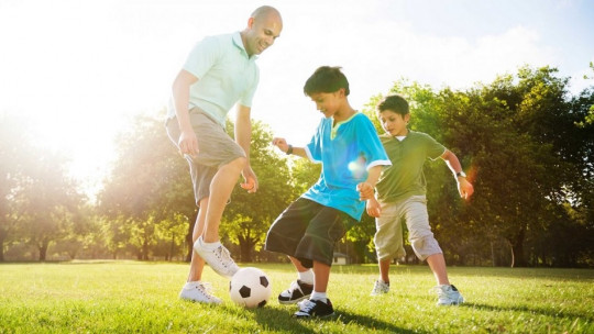 Padres e hijos jugando a fútbol.