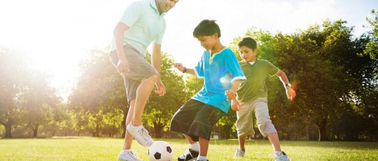 Padres e hijos jugando a fútbol.